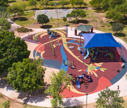 Aerial photo of Mitchell Park showing the artist-designed rubber playground surface, playground area, shade sail, ramada and basketball courts.